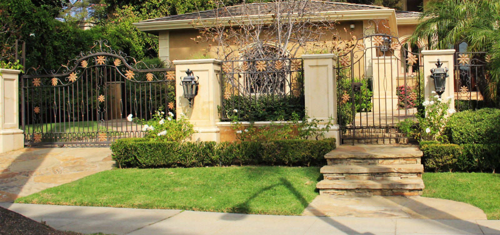 wrought iron electric gate and pedestrian gate with tropical flowers leaves Los Angeles